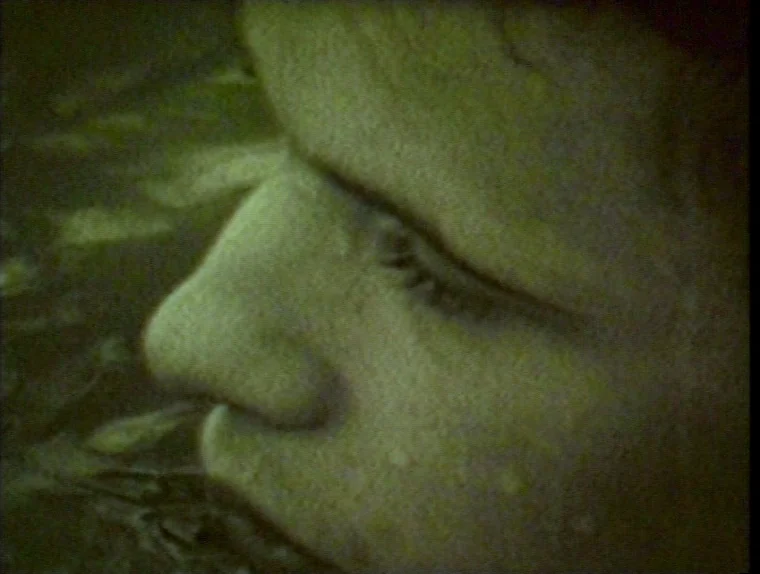 The Angelic Conversation (1985) movie still: closeup — A dark outdoor environment where water ripples around a partially submerged head. The subject…