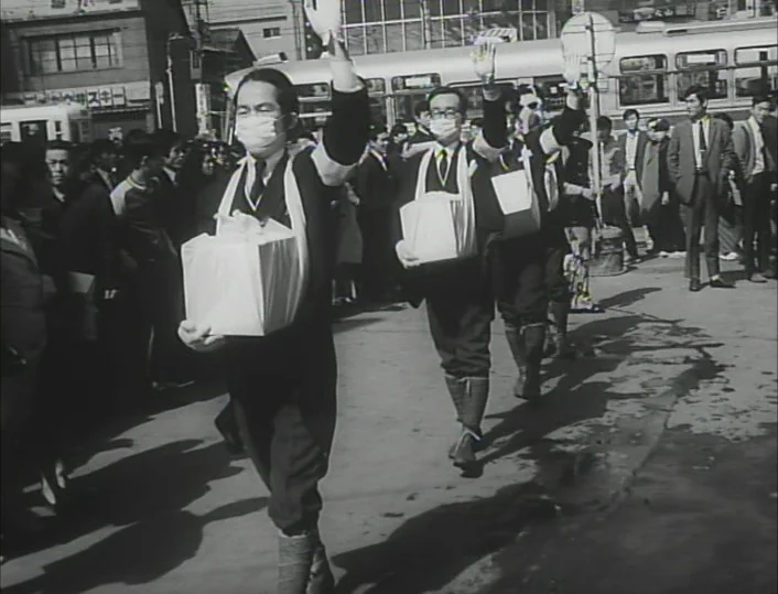 Funeral Parade of Roses (1969) movie still: fullbody — A street scene in a Japanese city featuring men walking in a formation. They carry white…