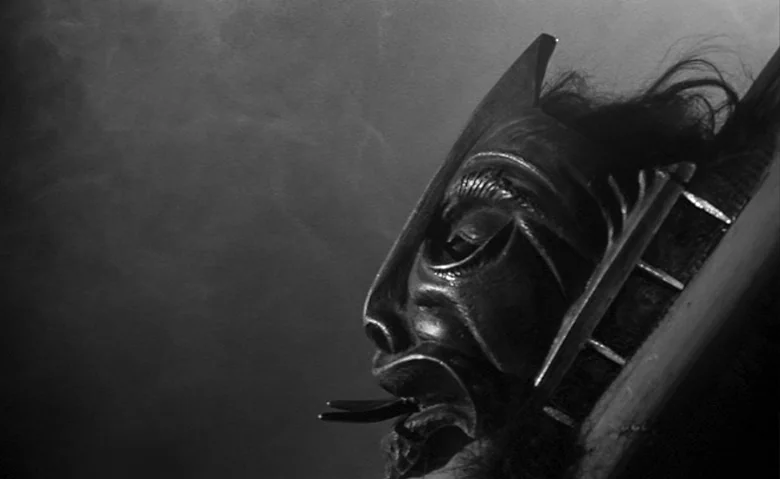 Black Sunday (1960) movie still: closeup — A dark, smoke-filled space contains a highly detailed wooden sculpture of a face. The carved mask shows a…