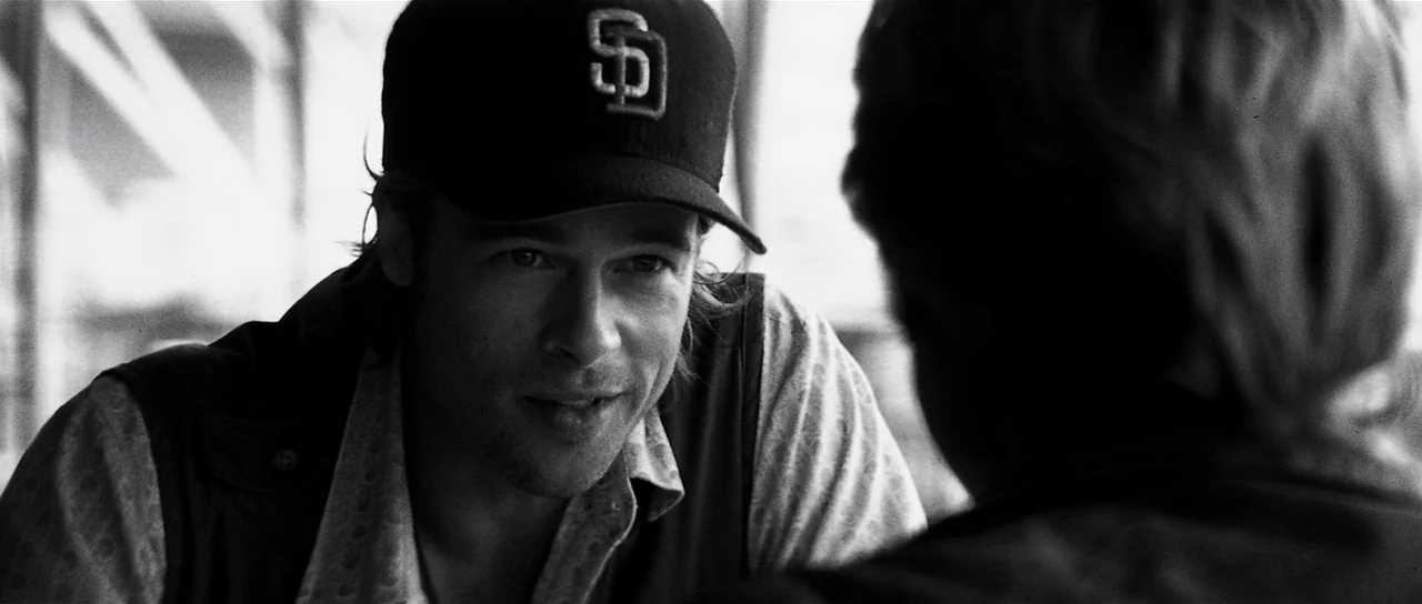 Spy Game (2001) movie still: medium — An interior space, likely a train car, features a man looking toward someone. The man wears a baseball cap and…