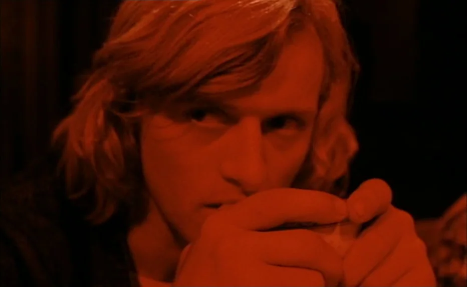 Turkish Delight (1973) movie still: closeup — A man sits in a dimly lit, red-saturated space. He holds a small cup in his hands.