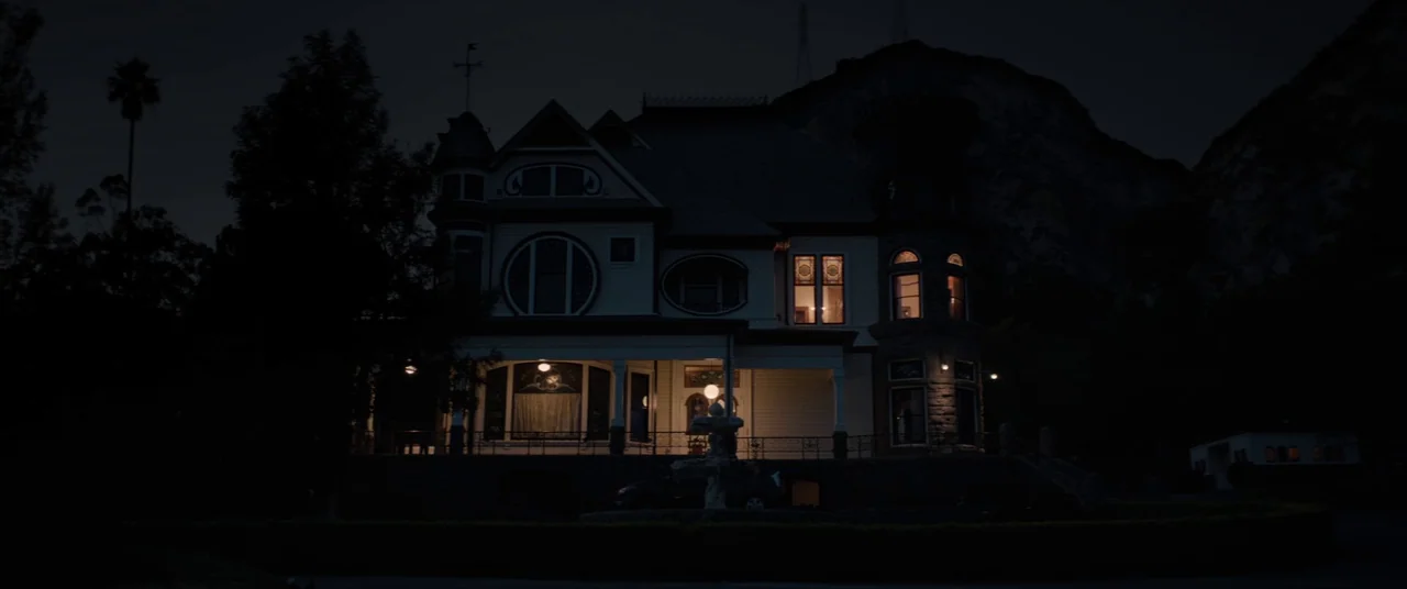 Tone Deaf (2019) movie still: establishing — A dark, multi-story Victorian-style house sits at the base of a shadowed mountain range. Several…