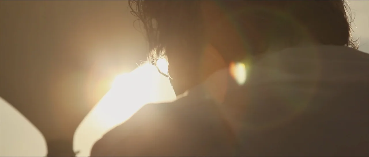 Garnet’s Gold (2014) movie still: closeup — An outdoor setting is illuminated by the intense light of the setting sun. A person viewed from behind…