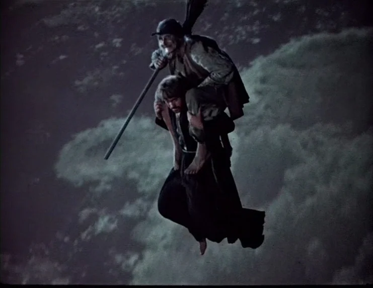 Viy (1967) movie still: fullbody — Two men fly through the night air while riding a wooden broomstick. They are suspended over a dimly lit, cloudy…