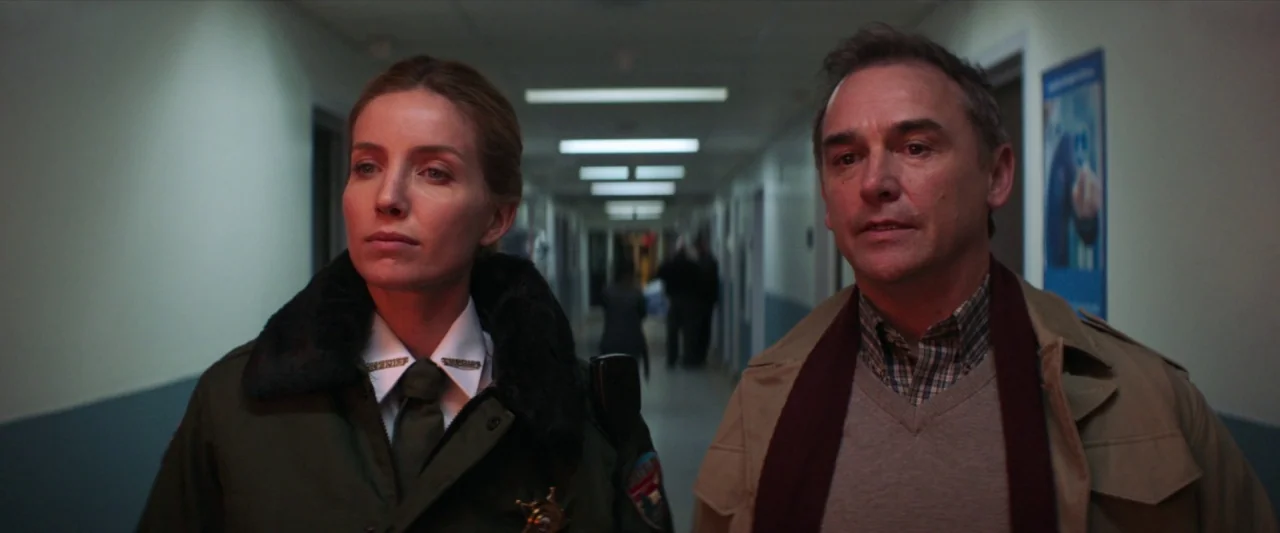 The Silencing (2020) movie still: medium — A long, institutional corridor with blue-painted walls and rows of overhead fluorescent lights. A…