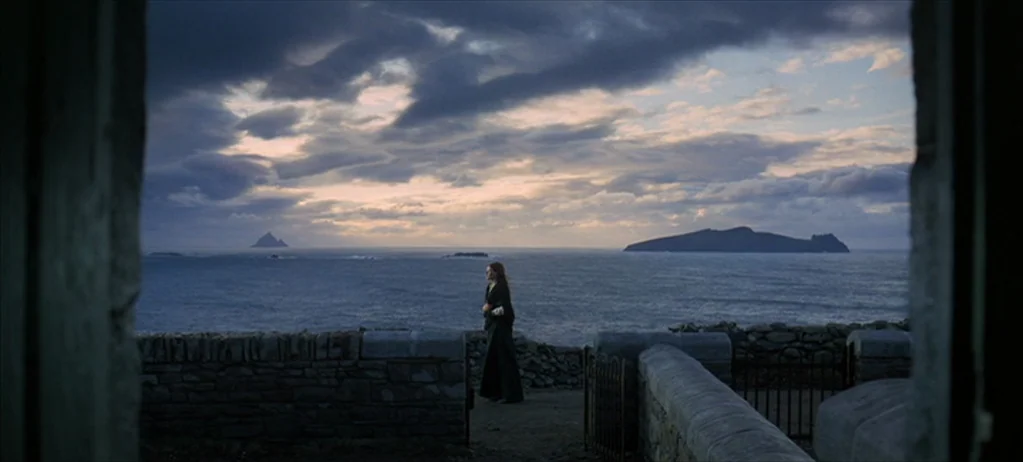 Ryan’s Daughter (1970) movie still: wide — A rocky coastal cliff overlooks a vast, choppy ocean under a dramatic cloudy sky. A lone woman in a long…