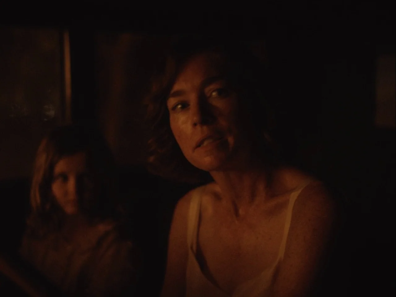 Blonde (2022) movie still: medium — The interior of a vehicle at night is engulfed in deep shadow. A woman in a tank top faces toward the passenger…