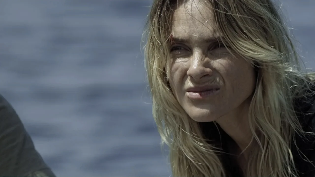 Capsized: Blood in the Water (2019) movie still: closeup — An open expanse of water serves as the backdrop for a close-up shot. A woman with blonde…