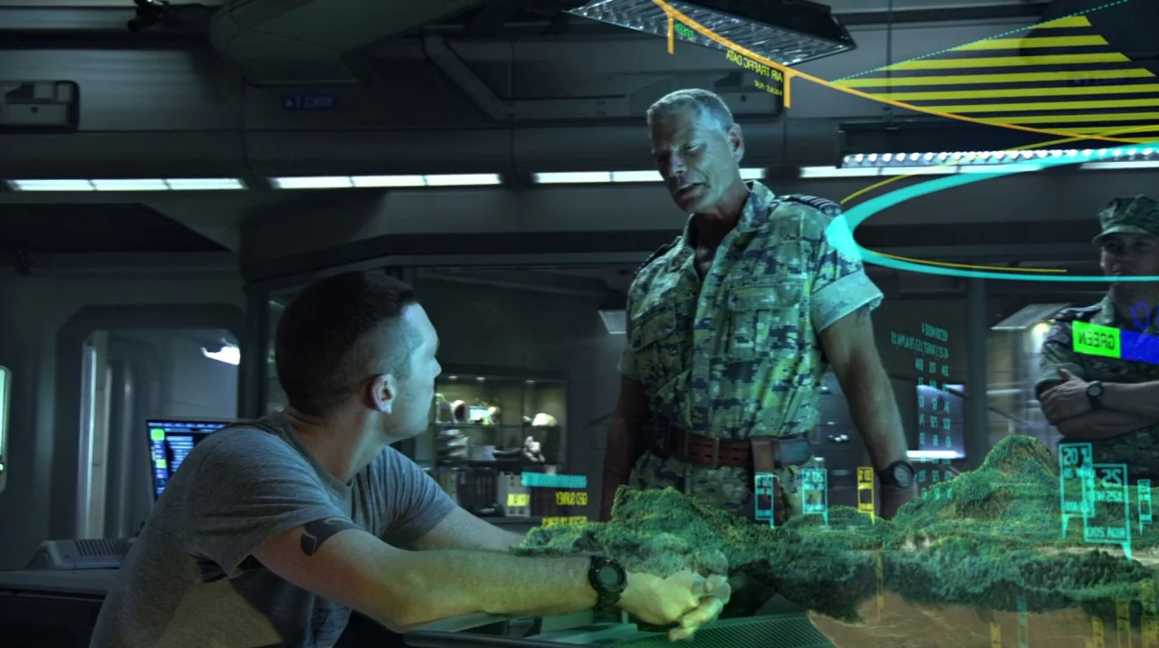 Avatar (2009) movie still: medium — A high-tech tactical briefing room features dark metallic surfaces and glowing holographic terrain maps. A stern…