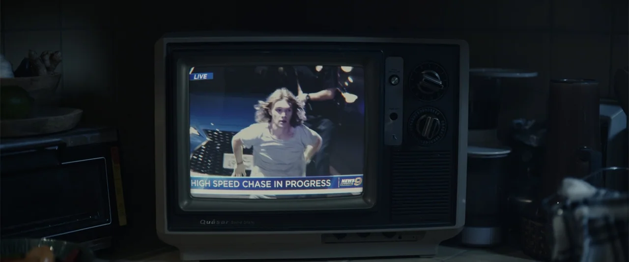 Moonfall (2022) movie still: medium — A dark kitchen counter holds a vintage Quasar television displaying a live news broadcast. The screen shows a…