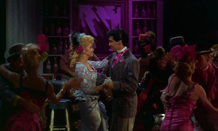 Frankie and Johnny (1966) movie still: medium — A bustling 1960s bar setting features shelves lined with glass bottles and purple lighting. A man…