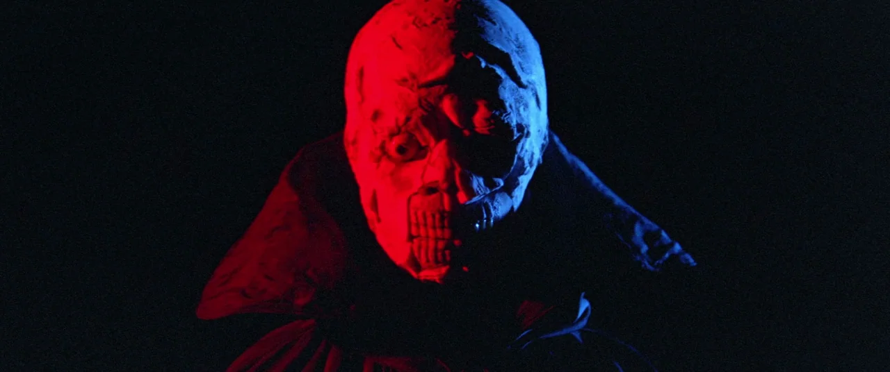 Encounter of the Spooky Kind (1980) movie still: closeup — A dark space with no visible background details. A pale disfigured face appears with…