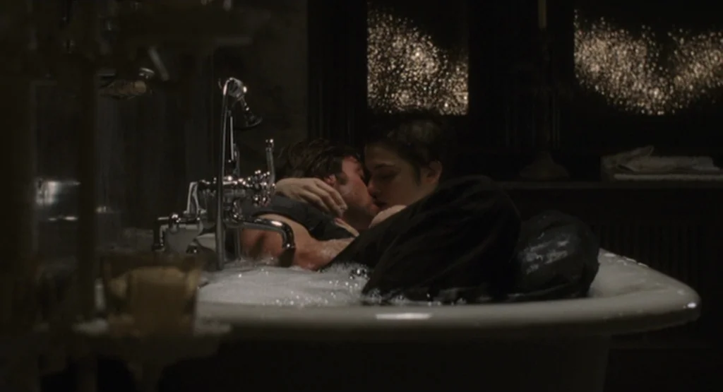 The Fountain (2006) movie still: medium — A dimly lit room with an old-fashioned clawfoot tub containing soapy water. A couple embraces and kisses…