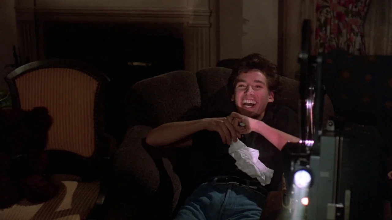 Friday the 13th: The Final Chapter (1984) movie still: medium — A dimly lit room contains an armchair occupied by a man and a film projector. The…