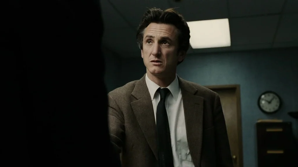 The Assassination of Richard Nixon (2004) movie still: medium — A dimly lit office features blue-toned walls, a wall clock, and a filing cabinet. A…