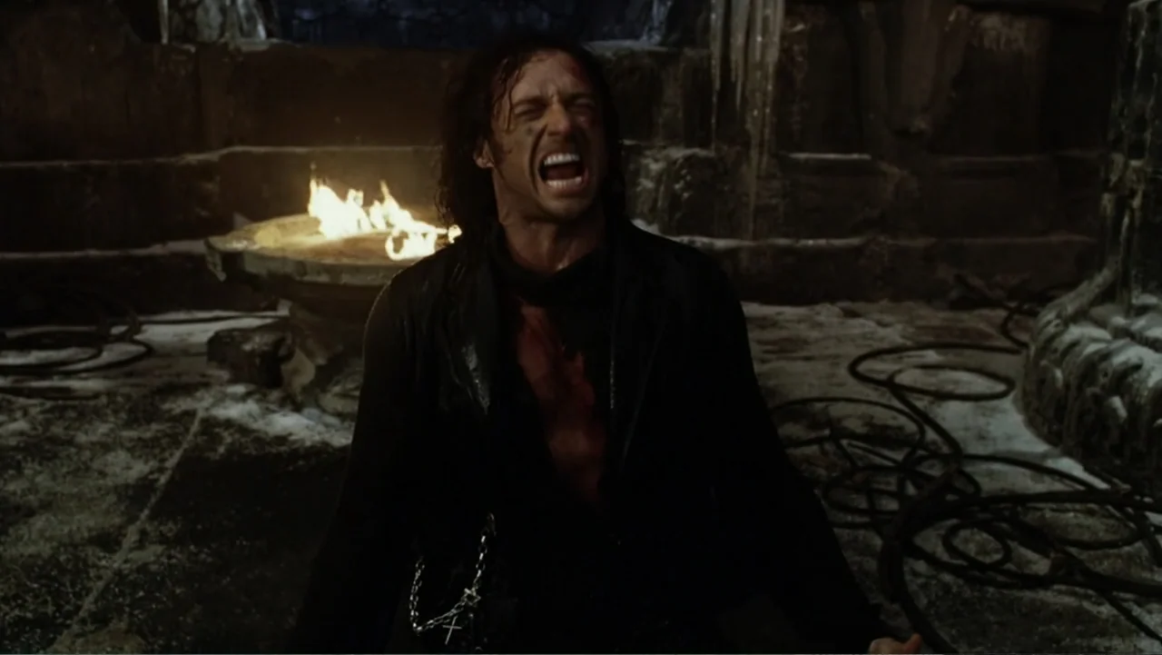 Van Helsing (2004) movie still: medium — A dark stone chamber features a large stone basin with a burning fire inside. A man stands in the…