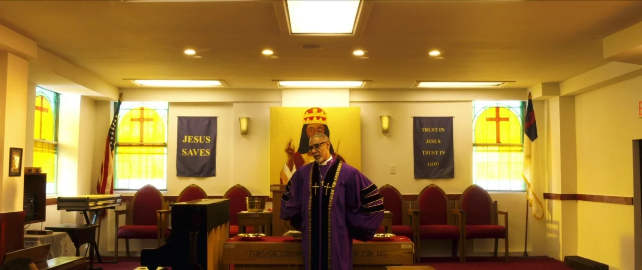 Da Sweet Blood of Jesus (2014) movie still: medium — An interior view of a church sanctuary with yellow-stained glass windows and blue banners. An…