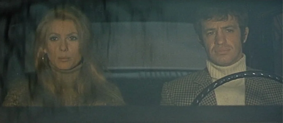 Mississippi Mermaid (1969) movie still: medium — The interior of a car shows a man and woman in the front seats. They both look forward through the…