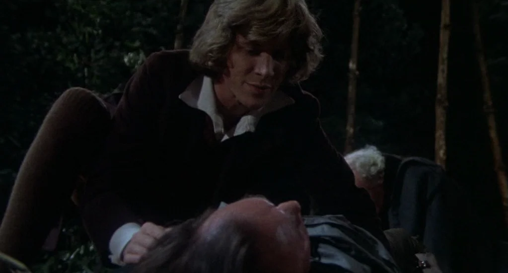 Demons of the Mind (1972) movie still: medium — A dark, wooded area at night with thin trees visible in the background. A young man with blonde hair…