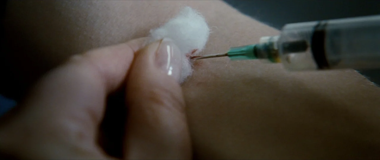 The Haunting in Connecticut (2009) movie still: closeup — A close-up view shows a medical procedure on a pale human forearm. A syringe needle…