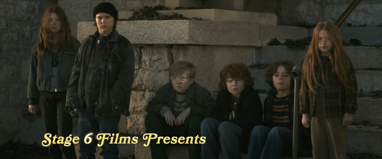 The Best Christmas Pageant Ever (2024) movie still: fullbody — Six children sit and stand on wide stone steps outdoors. They face the camera…