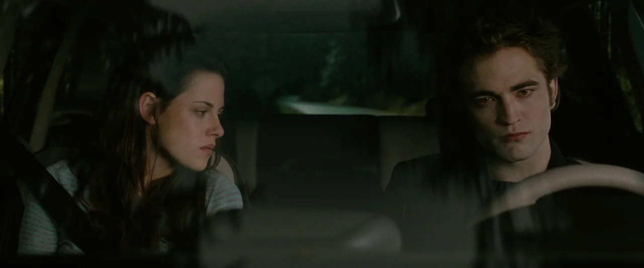 The Twilight Saga: New Moon (2009) movie still: medium — The interior of a car driving through a forested area on an overcast day. A man drives…