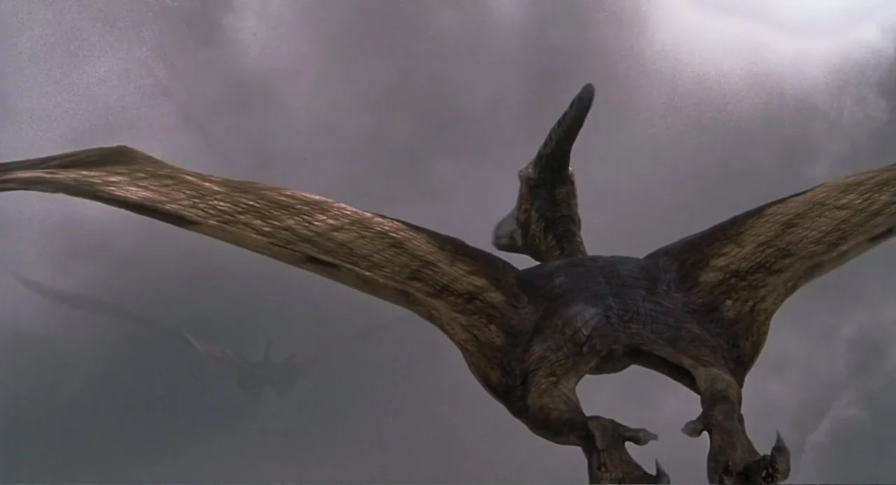 Jurassic Park III (2001) movie still: medium — A large prehistoric flying reptile wings its way through a thick, cloudy sky. A second smaller…