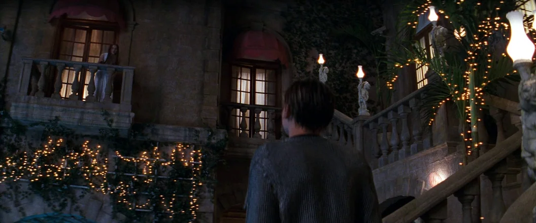 Romeo + Juliet (1996) movie still: wide — A stone mansion facade is decorated with string lights and climbing ivy at night. A young man stands in…