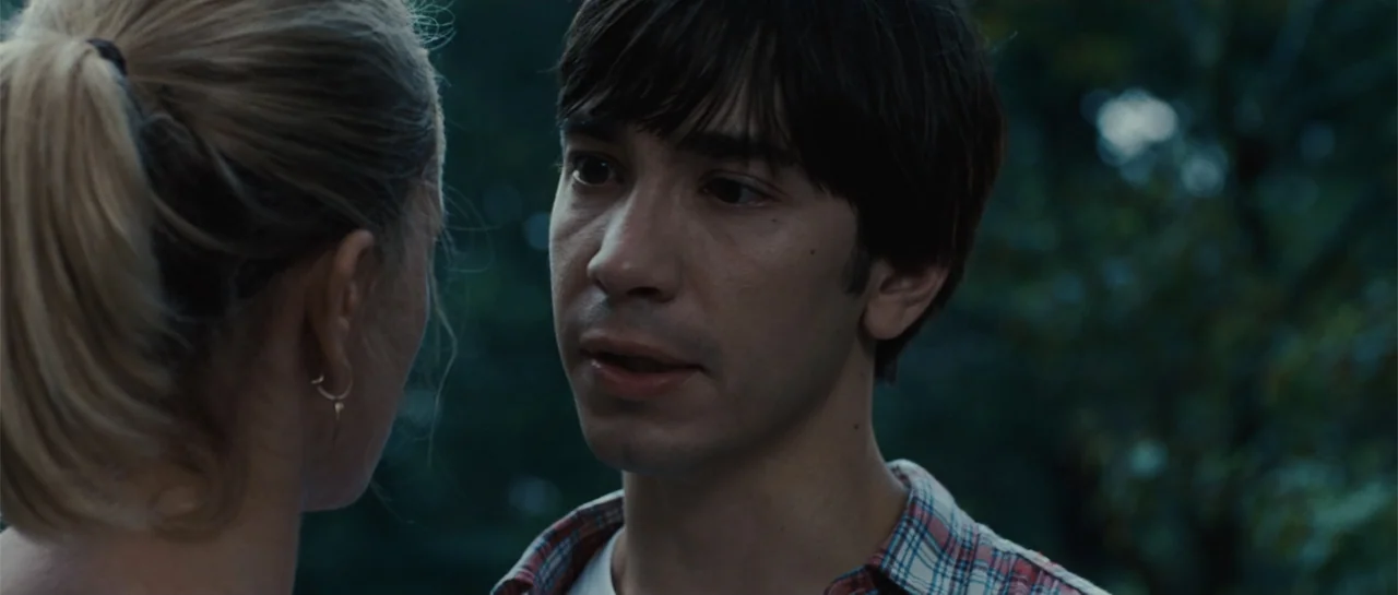 Going the Distance (2010) movie still: medium — Two individuals stand closely together outdoors surrounded by blurred natural greenery. The man…