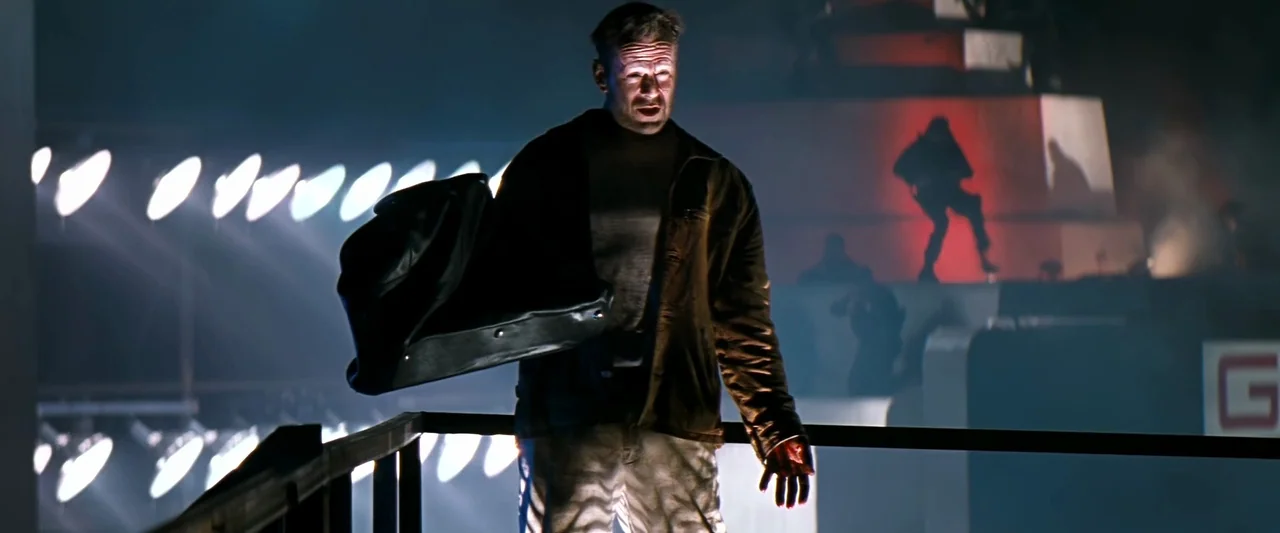 The Last Boy Scout (1991) movie still: medium — An industrial platform features bright white overhead lights and red background accents. A man in a…