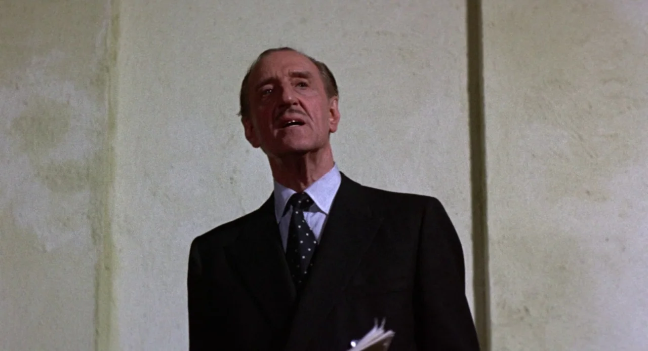 Queen of Blood (1966) movie still: medium — A man stands against a plain plaster wall in what appears to be a courtroom. The man addresses someone…