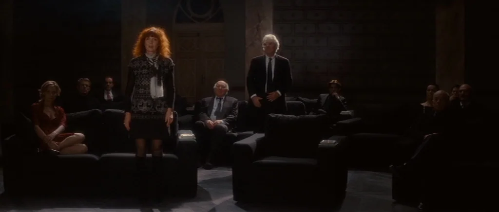 You Ain’t Seen Nothin’ Yet (2012) movie still: wide — A dark screening room features several rows of plush black sofas arranged for viewers. A woman…