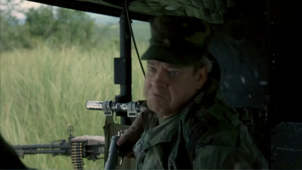 Behind Enemy Lines (2001) movie still: medium — An aging soldier sits inside the cabin of a transport helicopter overlooking grass fields. The man…