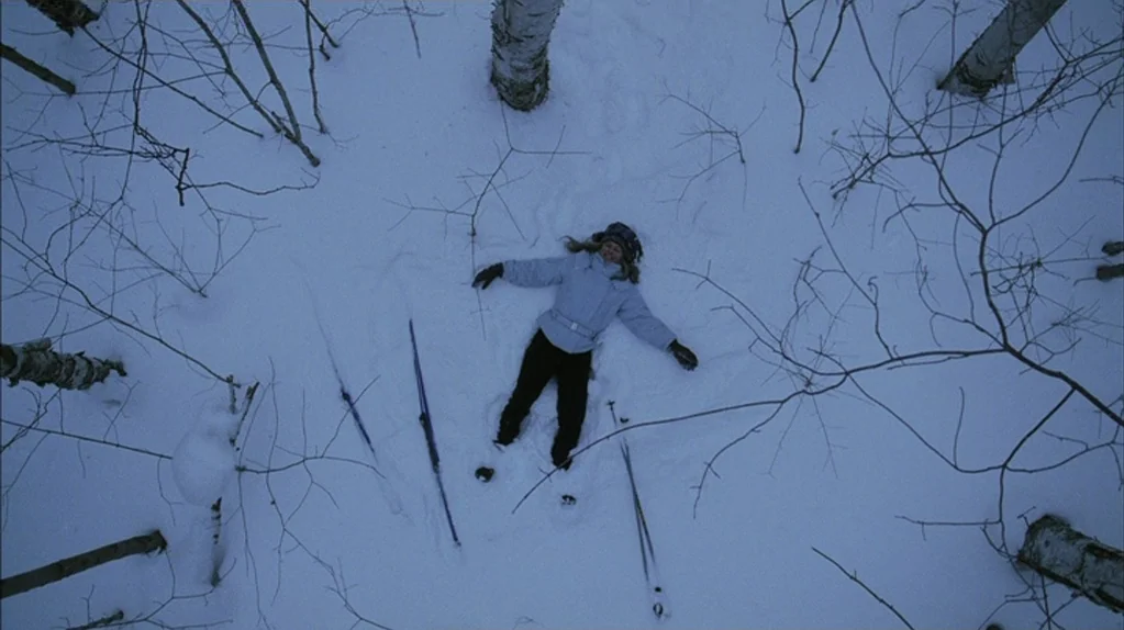 Away From Her (2006) movie still: fullbody — A snow-covered clearing within a stand of thin birch trees. A woman lies flat on her back in the center…