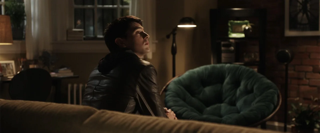Final Destination 5 (2011) movie still: medium — A dimly lit room features a brick wall, a teal saucer chair, and a lamp. A young man wearing a…