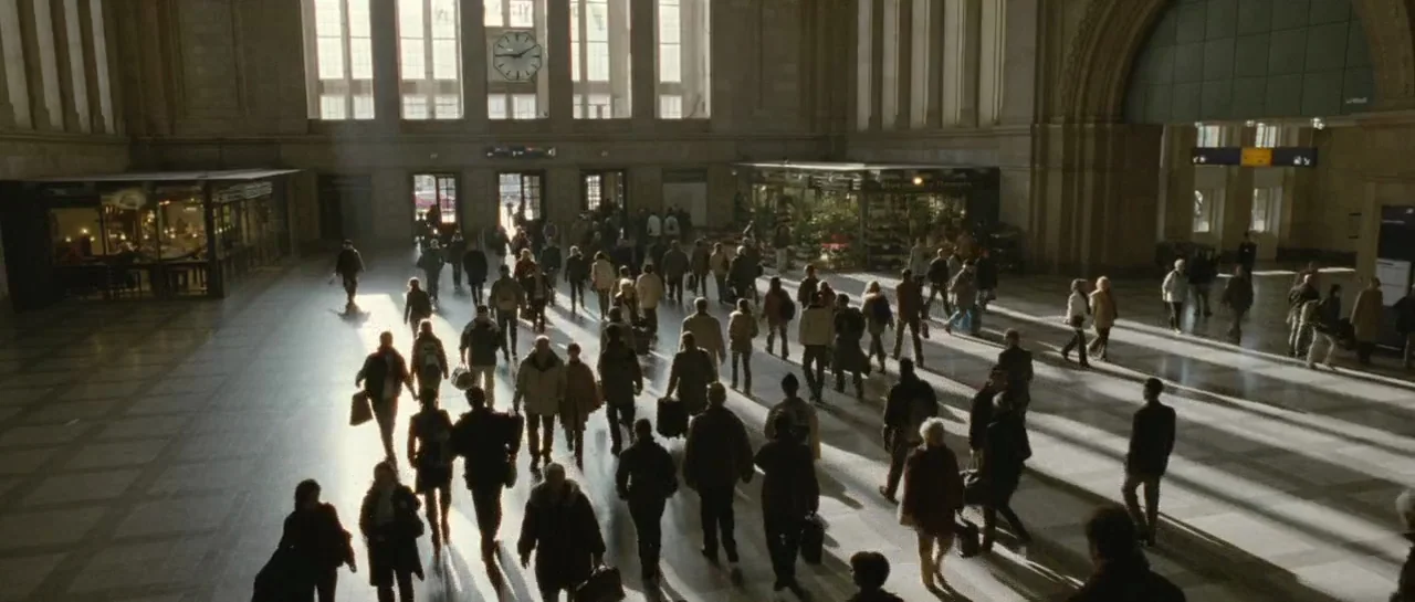 Mr. Nobody (2009) movie still: wide — A spacious stone concourse of a train station features large arched windows and a clock. Numerous commuters…