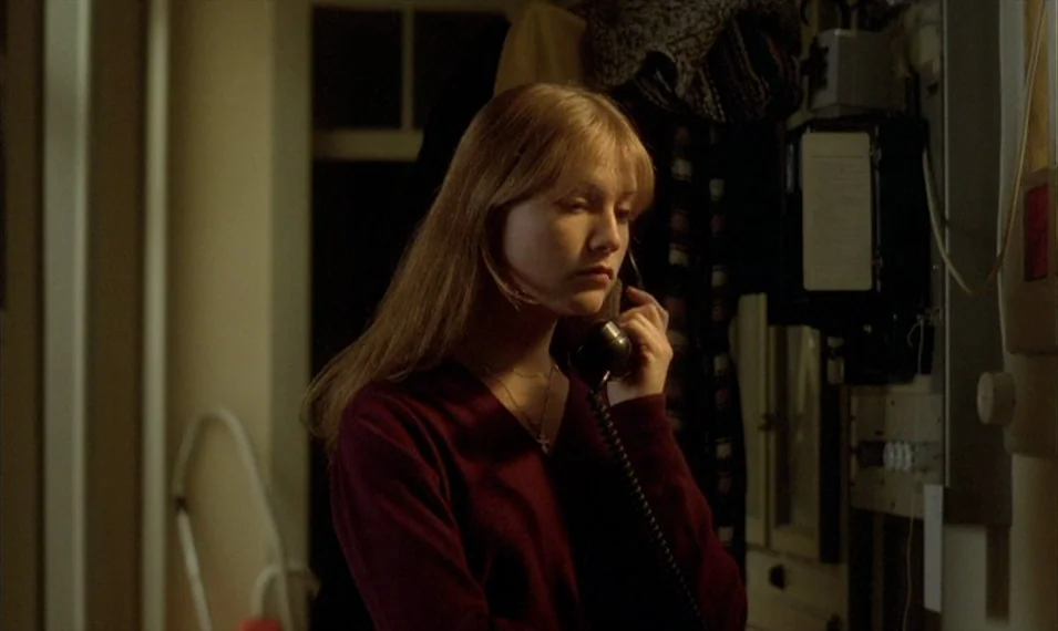 Every Man for Himself (1980) movie still: medium — A dimly lit indoor space with a wall-mounted telephone and visible electrical wiring. A young…