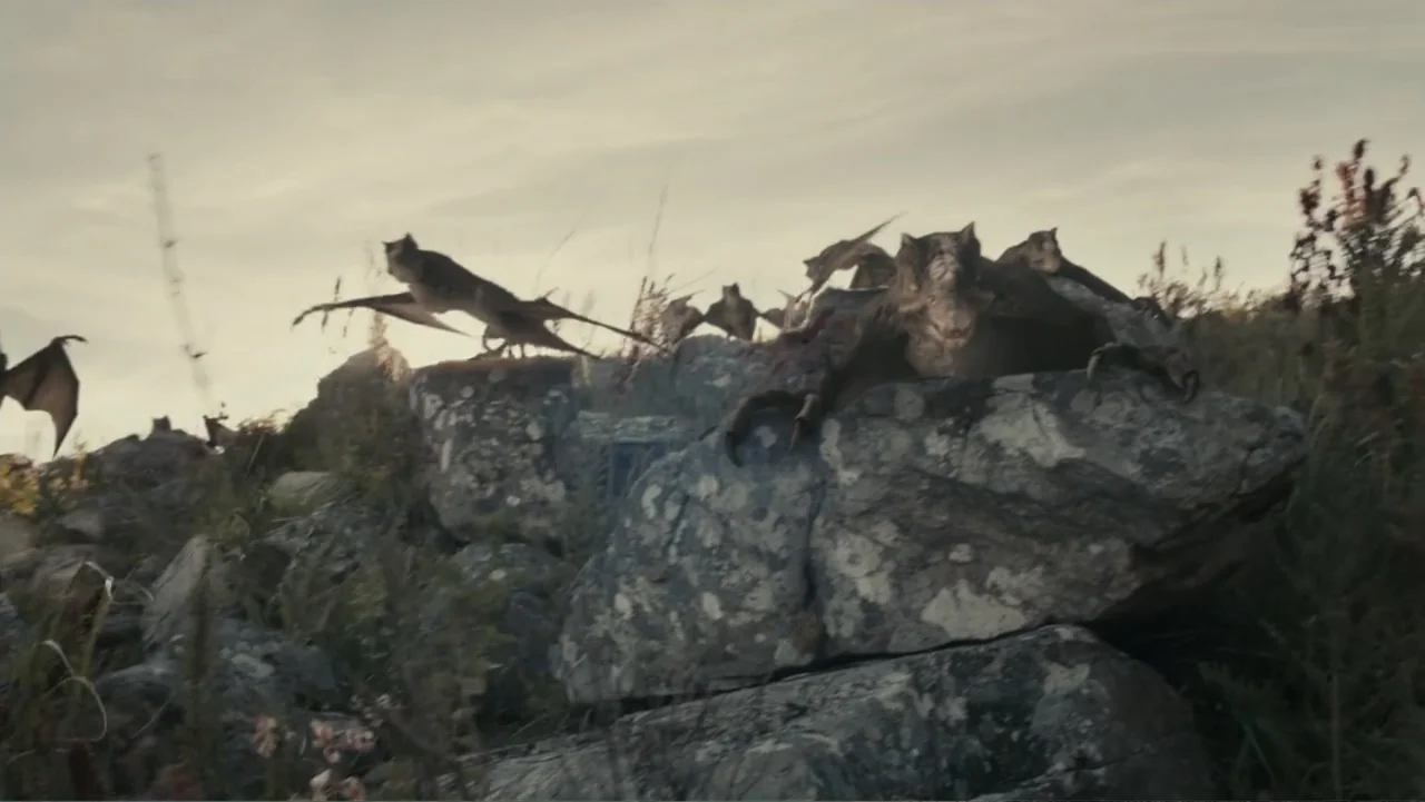 The Dinosaur Project (2012) movie still: wide — A rocky hillside at dusk features sparse grasses growing between large, lichen-covered stone…