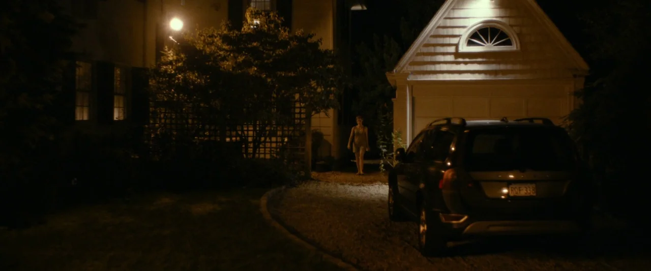 The Disappearance of Eleanor Rigby: Her (2014) movie still: wide — A residential driveway at night features a dark SUV parked near a garage. A woman…
