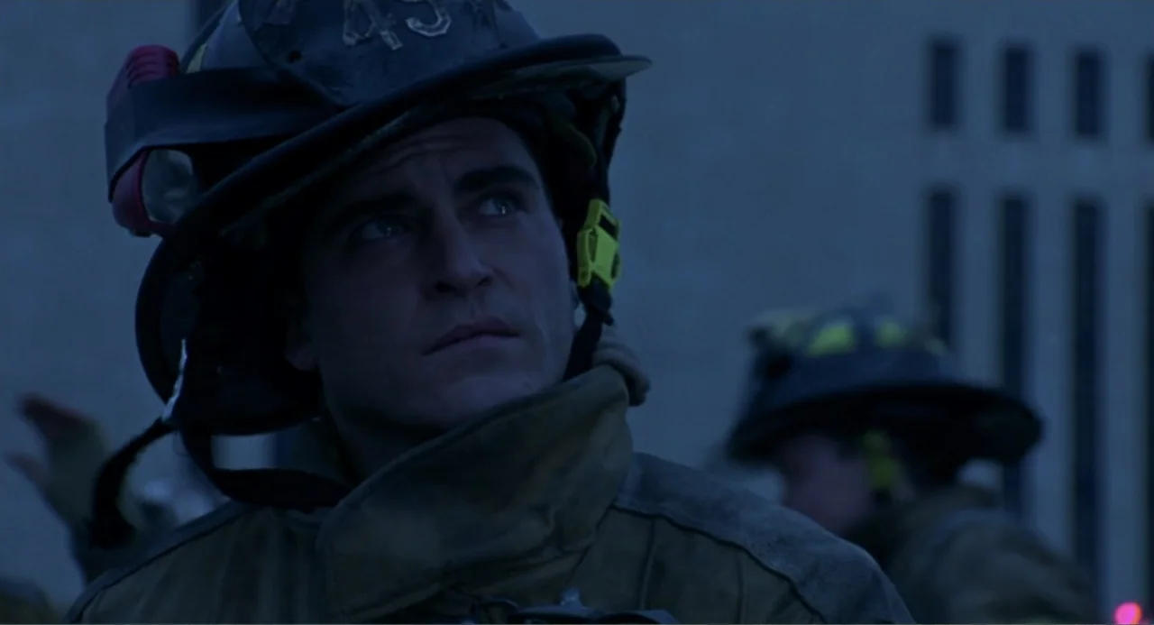 Ladder 49 (2004) movie still: medium — A firefighter in protective gear stands outdoors at night near an architectural structure. The man looks up…