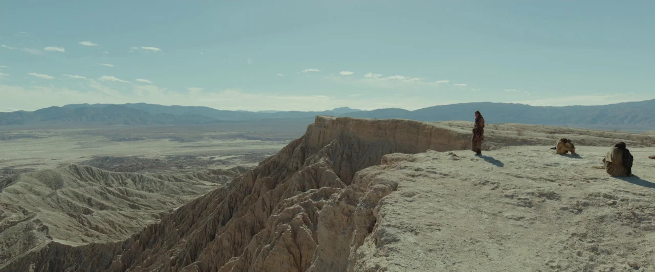 Last Days in the Desert (2015) movie still: wide — A vast, eroded arid desert landscape with layered sedimentary rock formations and dry mountains.…