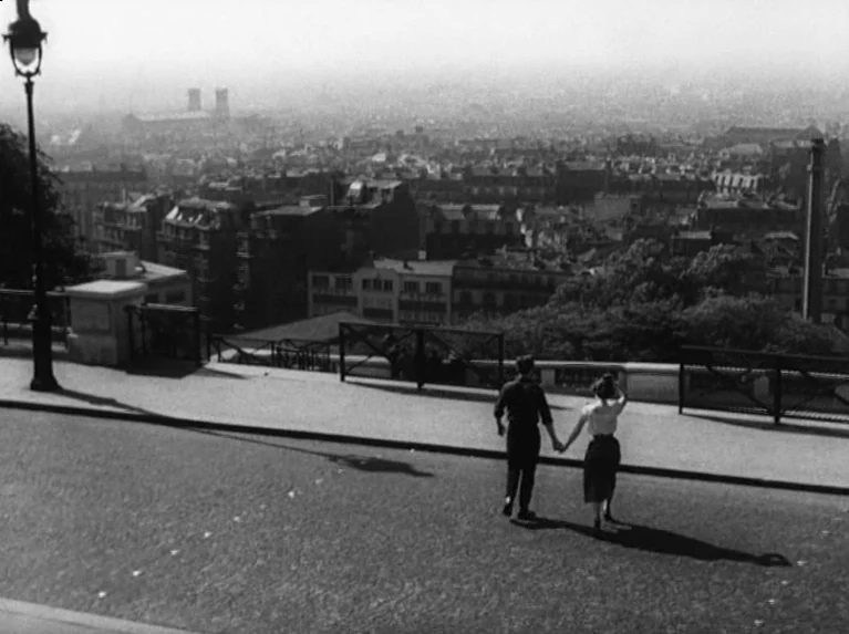 Waiting Women (1952) movie still: wide — A wide city street overlooks a sprawling urban landscape under a hazy sky. A couple walks hand in hand…