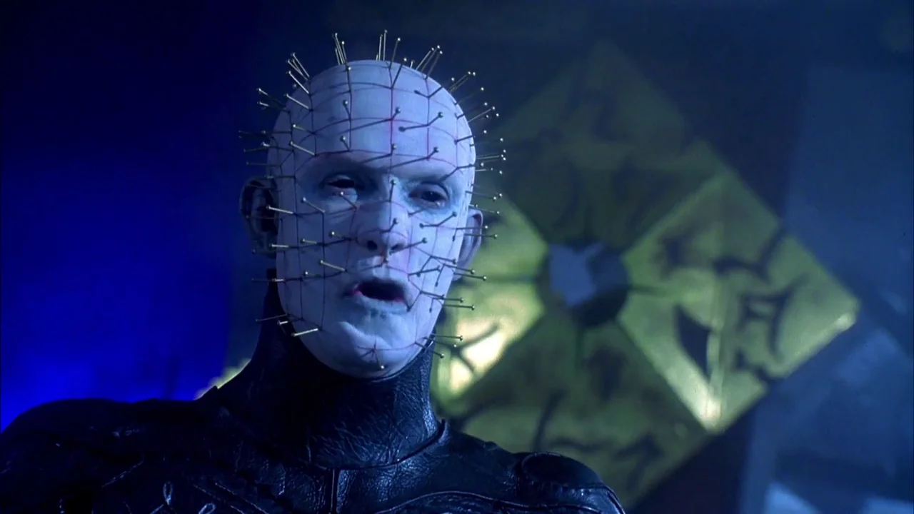 Hellraiser: Bloodline (1996) movie still: closeup — A dark space features a pale figure with pins embedded in his skin. The figure speaks while a…