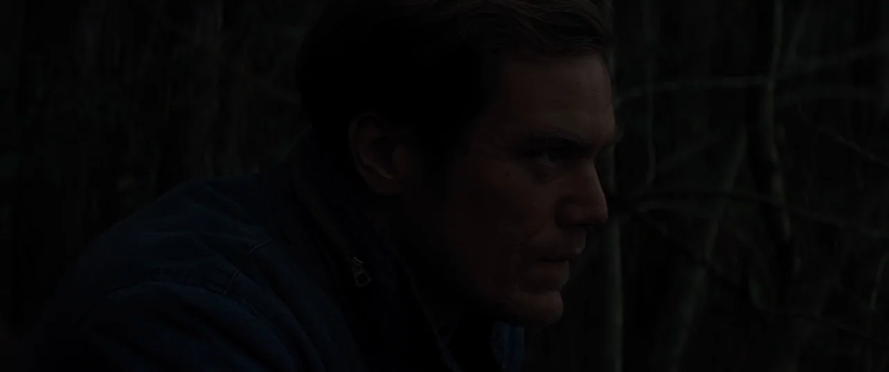 Midnight Special (2016) movie still: medium — A man stands in a dark wooded area at night among shadowy, indistinct branches. He looks to the right…