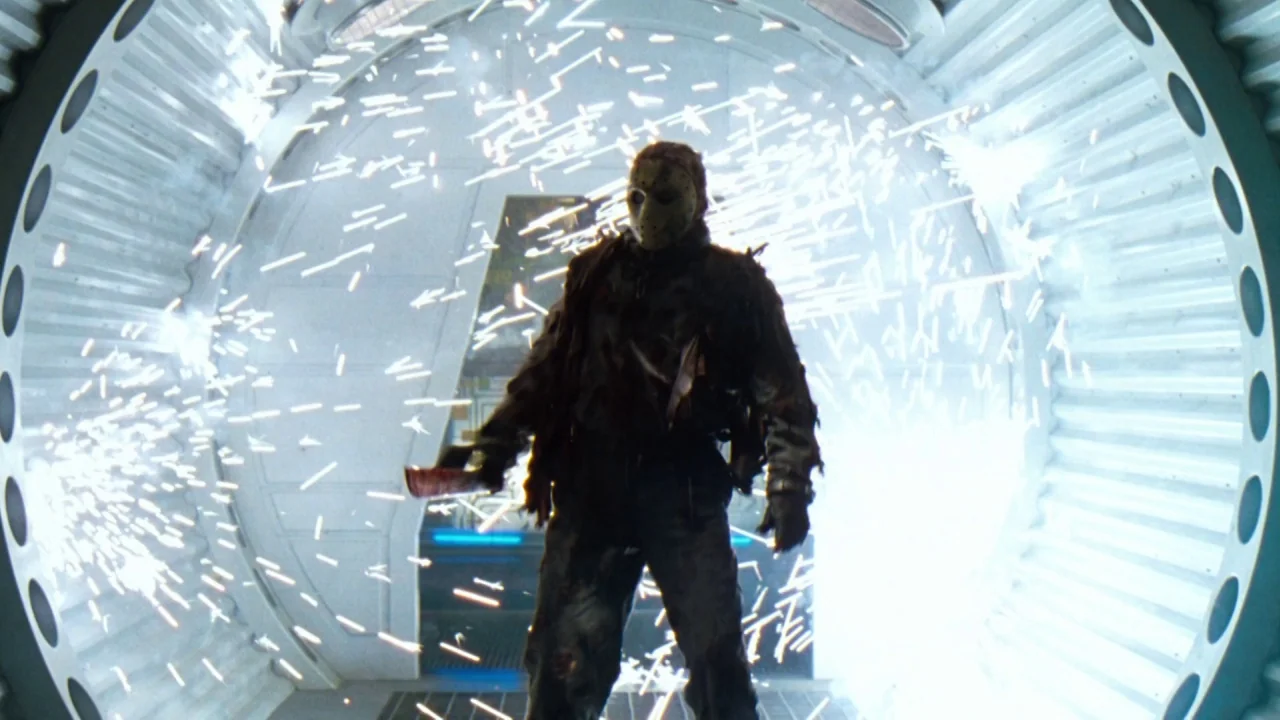 Jason X (2001) movie still: fullbody — A metal-walled circular corridor inside a spaceship is filled with chaotic showering white sparks. A tall,…