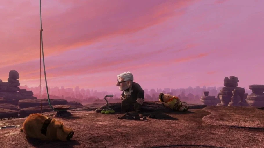 Up (2009) movie still: wide — A rocky, uneven plateau stretches toward a distant hazy mountain range during sunset. An elderly man, a boy, and a dog…