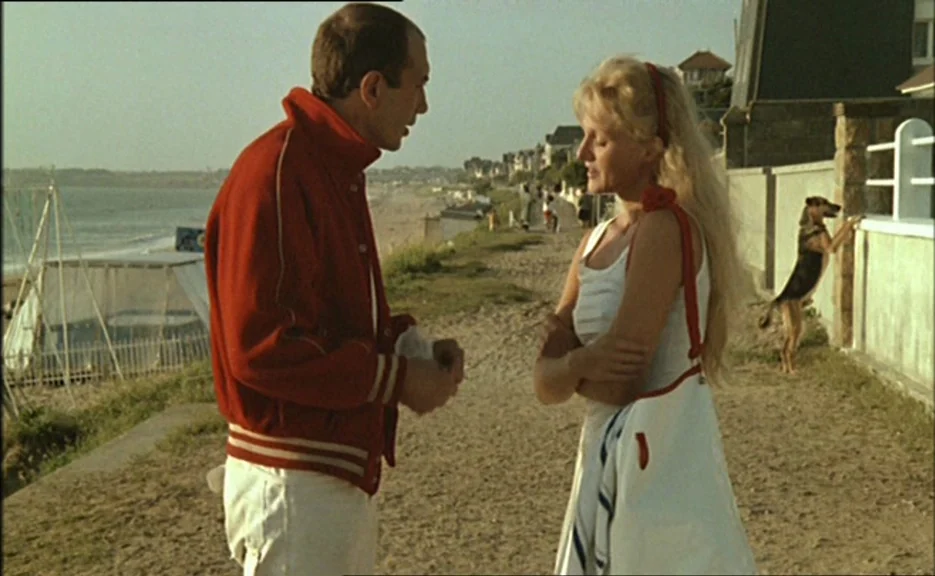 Pauline At the Beach (Pauline à la plage) (1983) movie still: medium — A sandy seaside promenade overlooks the ocean with houses visible along the…