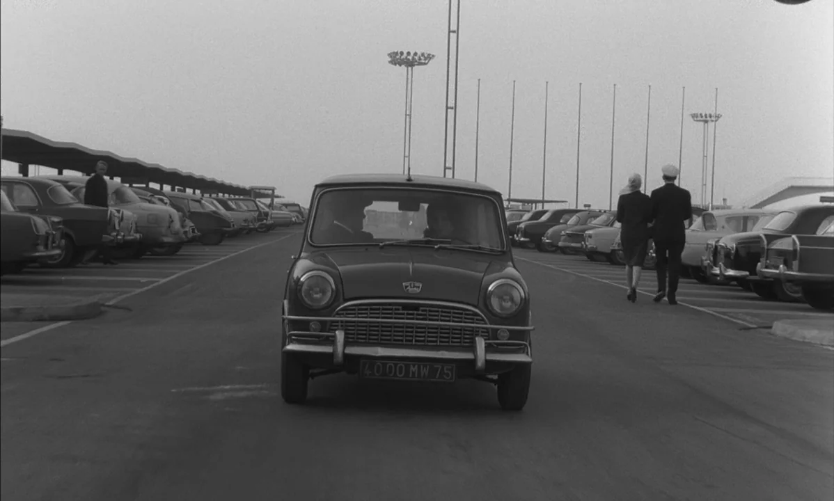 La Peau Douce (The Soft Skin) (1964) movie still: wide — An expansive, paved parking lot holds numerous vintage automobiles parked in orderly rows.…