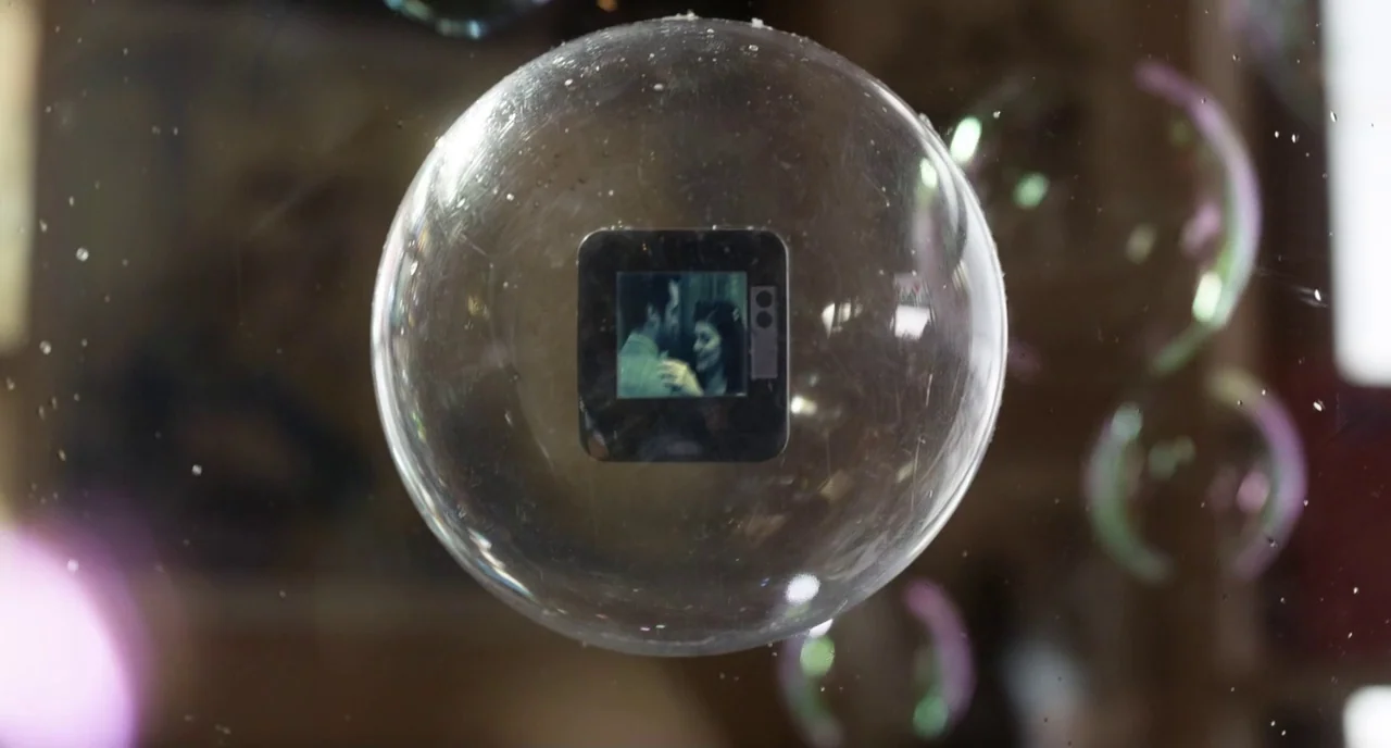 Mood Indigo (2013) movie still: closeup — A translucent soap bubble floats centrally in the frame. Inside the bubble is a square photographic slide…