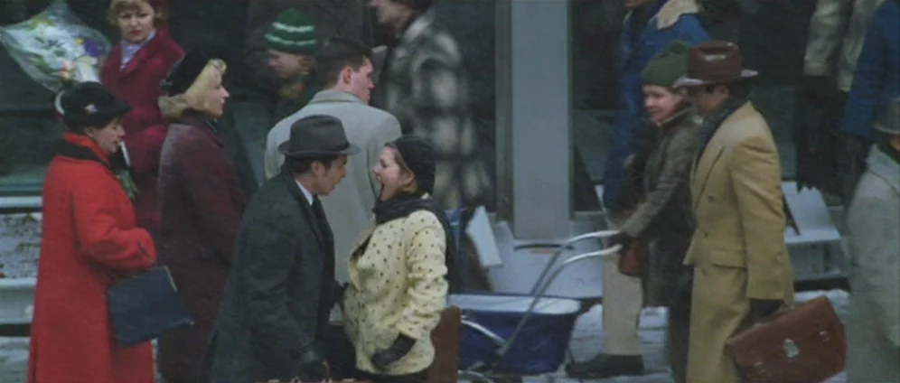 Confessions of a Dangerous Mind (2002) movie still: medium — A crowded outdoor platform features people in winter attire near a baby carriage. A man…